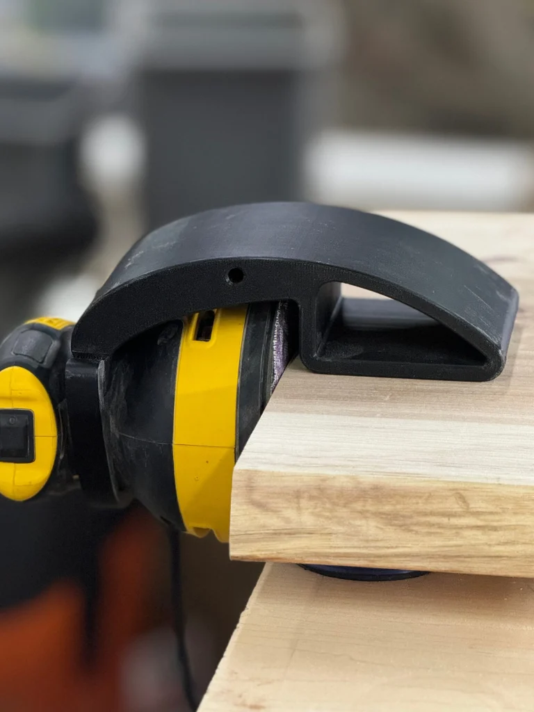 Black Xact90 Pro guide on a DeWalt sander at the edge of a maple board